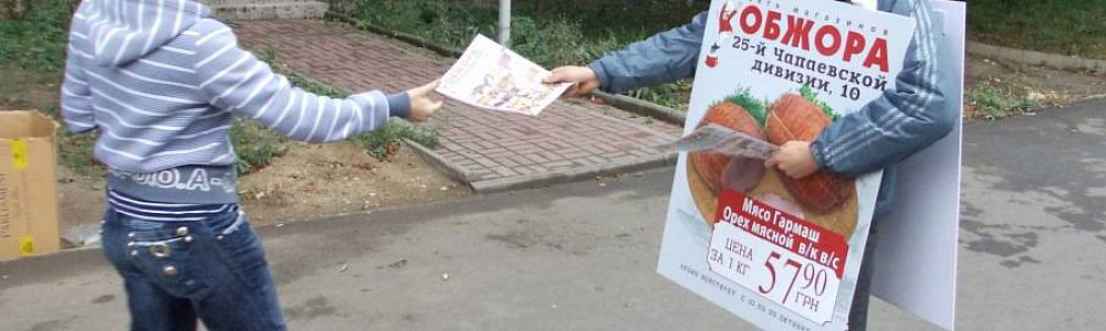 Промоутер сэндвич-мэн раздает листовки на улице